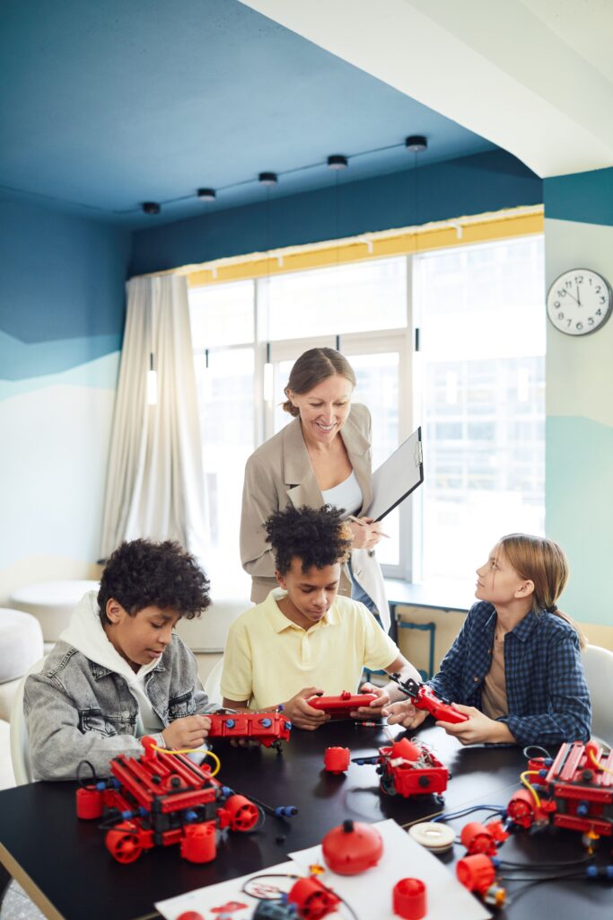 Children engaging in a hands-on STEM robotics class with a teacher guiding them.